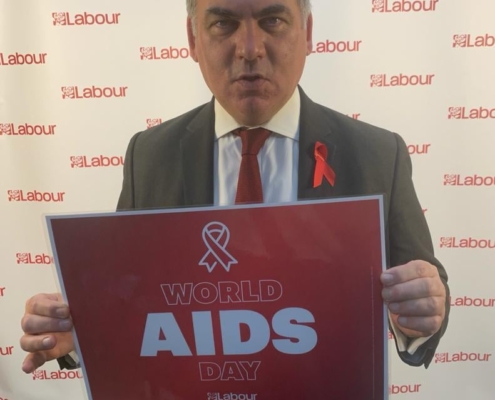 Bambos holding a placard in support of World AIDS Day