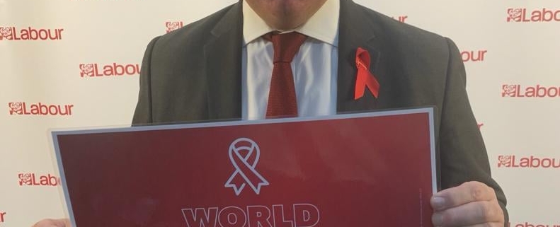 Bambos holding a placard in support of World AIDS Day