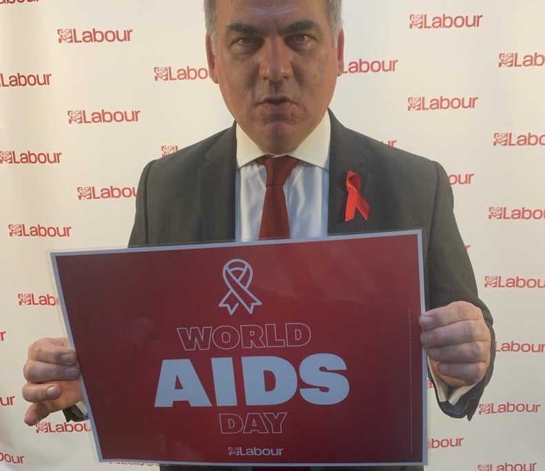 Bambos holding a placard in support of World AIDS Day