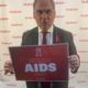 Bambos holding a placard in support of World AIDS Day